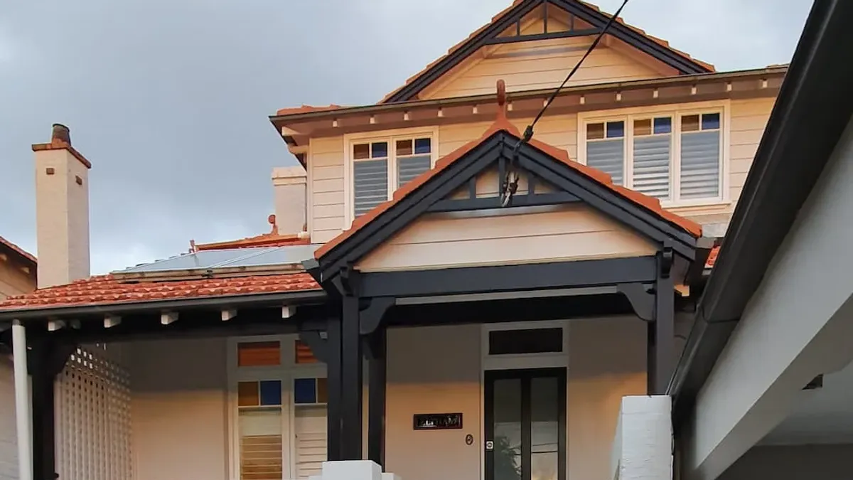 Freshly painted Federation home in Sydney with cream weatherboards and black timber trims under an overcast sky